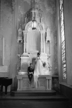 black and white photograph of bride and groom sitting on the alter in an old church