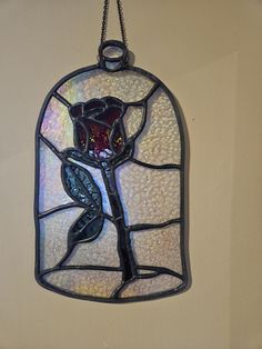 a stained glass window hanging on the side of a wall with a flower in it