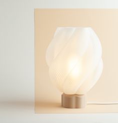 a white lamp sitting on top of a table next to a square piece of paper