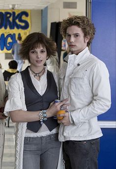 two people standing next to each other holding oranges