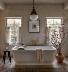 a large white bath tub sitting in a bathroom next to two vases filled with flowers