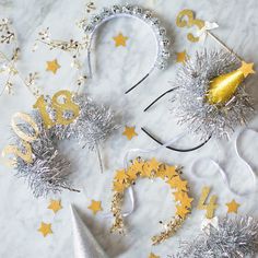 some silver and gold decorations on a white marble table with stars, tinsels and ribbons