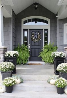 front porch with potted plants and wreaths on the steps leading up to the door