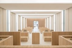 an empty room with benches and tables in the center, along with light wood paneling on the walls