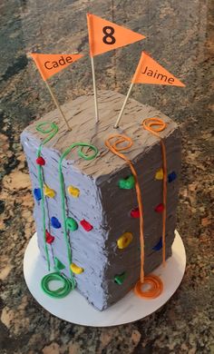 a cake made to look like a cube with flags on top and ribbons around the edges