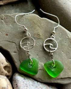 *Genuine Lake Michigan Sea Glass Dangle Earrings** About:  Discover the serene beauty of Lake Michigan with these exquisite handmade Dangle earrings, crafted from genuine found sea glass. Each piece of sea glass has been naturally tumbled by the gentle waves, resulting in unique, frosted jewels that capture the essence of the lake's pristine shores. Carefully selected for their color and clarity, these sea glass gems are paired with silver wave charm and nickel-free silver earrings, ensuring both elegance and comfort. Embrace the timeless allure of nature's artistry with these one-of-a-kind earrings, perfect for adding a touch of coastal charm to any outfit. Specifications: -Earring length: approximately 2 inches  -Earring Backing: Hooks -Materials: Genuine Lake Michigan sourced Sea Glass, Handmade Dangle Earrings, Earrings Handmade Dangle, Coastal Charm, Glass Gems, Lake Michigan, Bright Green