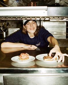 a woman sitting at a counter with two plates of food in front of her smiling