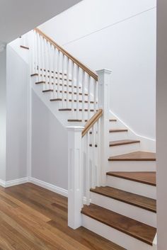 a white staircase with wooden handrails and wood flooring in an empty room