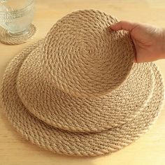 a hand is holding the top of two straw hats next to a glass of water