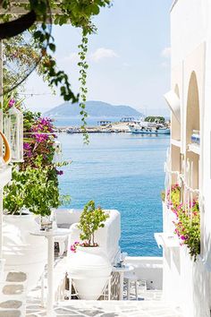 an alley way with tables and chairs overlooking the water in front of some white buildings