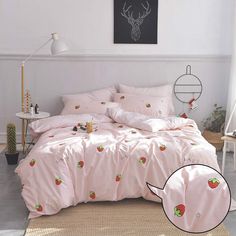 a bed with pink sheets and strawberrys on it, next to a white wall