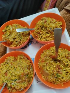 four orange bowls filled with food on top of a white tray