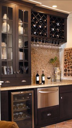 a kitchen filled with lots of wine bottles and glasses on top of the cupboards