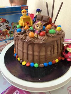 there is a chocolate cake with toy figures on it and other toys in the background