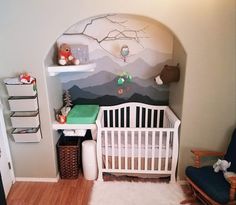 a baby's room with a white crib and mountain mural