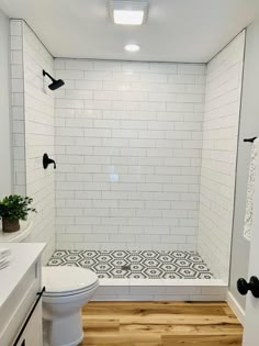 a white toilet sitting next to a bath tub in a bathroom on top of a hard wood floor