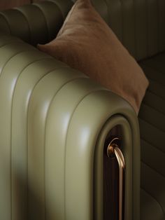 a green leather couch with a brown pillow on it's armrest and back