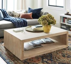 a living room with a couch, coffee table and books on the shelf in front of it