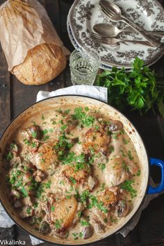 a pan filled with chicken and mushrooms covered in gravy on top of a wooden table