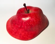 a red apple sitting on top of a white table