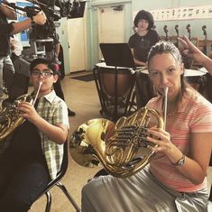 a woman playing the french horn in front of children