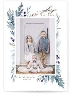 two children standing in front of a white door with greenery on it and an evergreen wreath