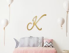 a white room with balloons and a gold monogrammed k on the wall