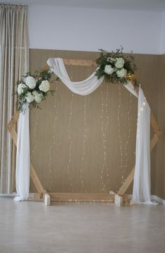 the wedding arch is decorated with white flowers and greenery for an elegant touch to the reception space