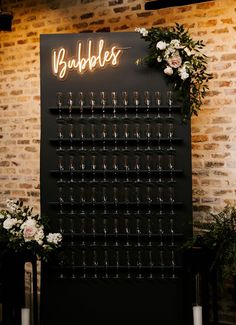 a wall mounted wine glass rack with candles and flowers on it in front of a brick wall