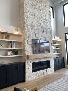 a living room with a large stone fireplace and built - in shelving units on the wall