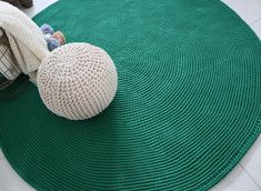 a green round rug with a white ball on the floor next to some blankets and other items