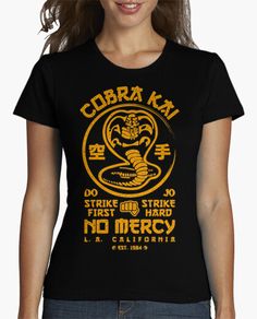 a woman wearing a black cobra t - shirt with yellow lettering on the front and back