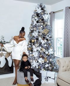 a woman standing next to a little boy in front of a christmas tree