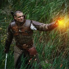 a man dressed in medieval armor holds out his hand to light up the firework