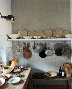 a kitchen with pots and pans hanging on the wall next to a wooden table