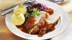 a white plate topped with meat, potatoes and gravy