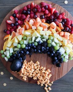 a wooden platter filled with fruit and nuts