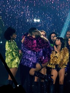 group of women in sequin outfits on stage with confetti falling from the ceiling