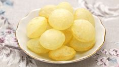 a white bowl filled with lemons sitting on top of a floral cloth covered tablecloth