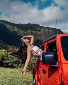 a woman leaning on the side of an orange jeep