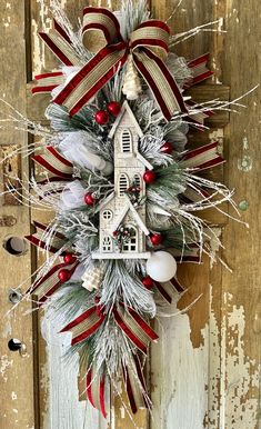 a christmas wreath hanging on the side of a door with a house and decorations around it