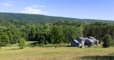 a house in the middle of a field surrounded by trees