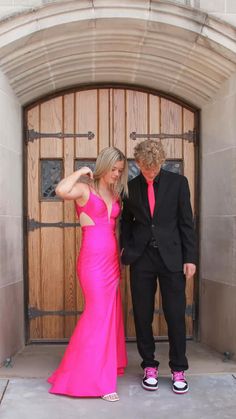 a woman in a pink dress standing next to a man in a black suit