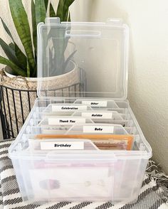 a plastic container filled with lots of notes and folders next to a potted plant