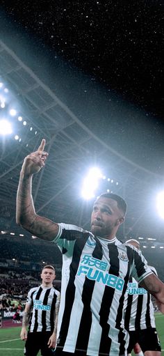 a man standing on top of a soccer field with his hand up in the air