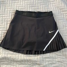 a black tennis skirt with white nike logo on the side, laying on a bed