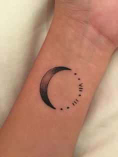 a small wrist tattoo with the moon and stars on it's left arm, in black ink