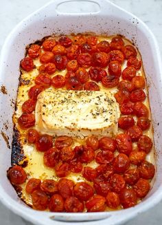 a casserole dish with tomatoes and fish in it