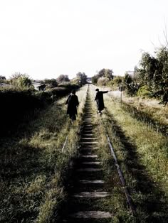 two people walking down a path in the grass