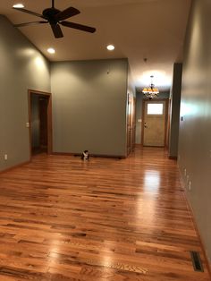 an empty living room with hard wood flooring and a ceiling fan in the corner